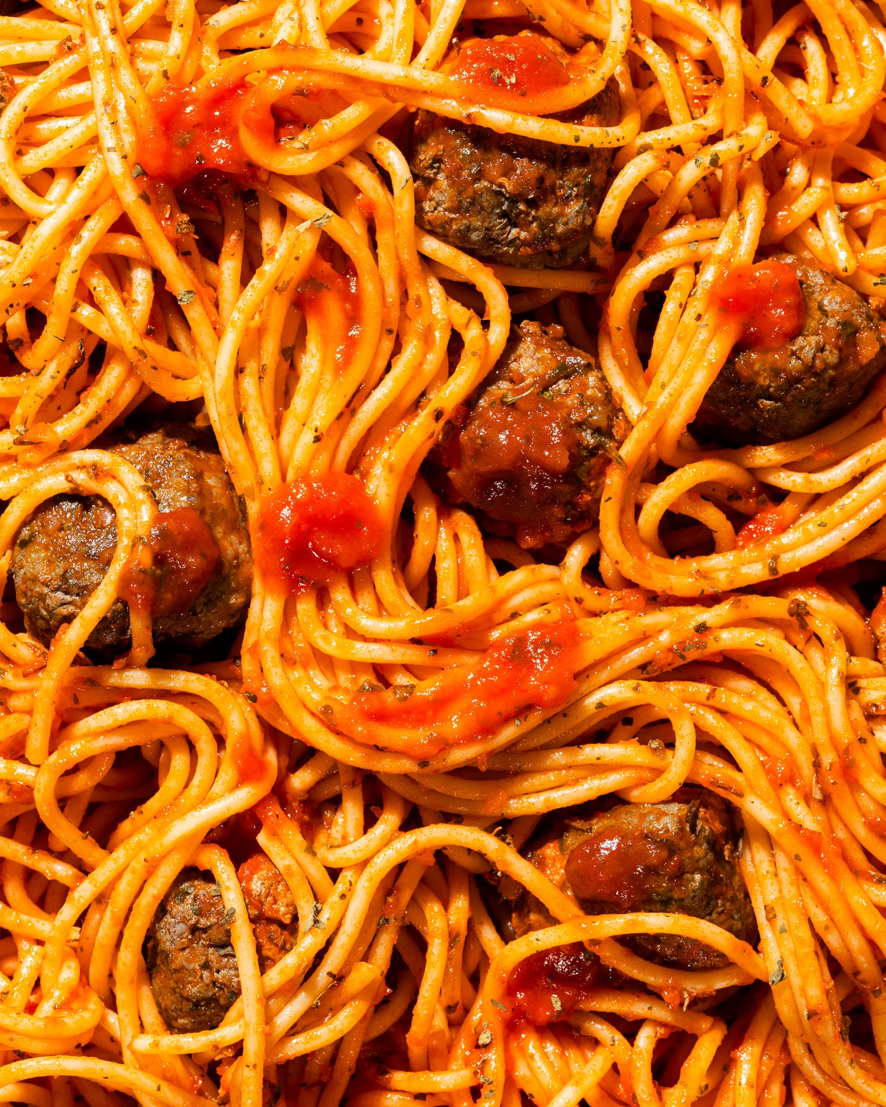 An overhead frame of spaghetti in tomato sauce with meatballs filling the whole frame