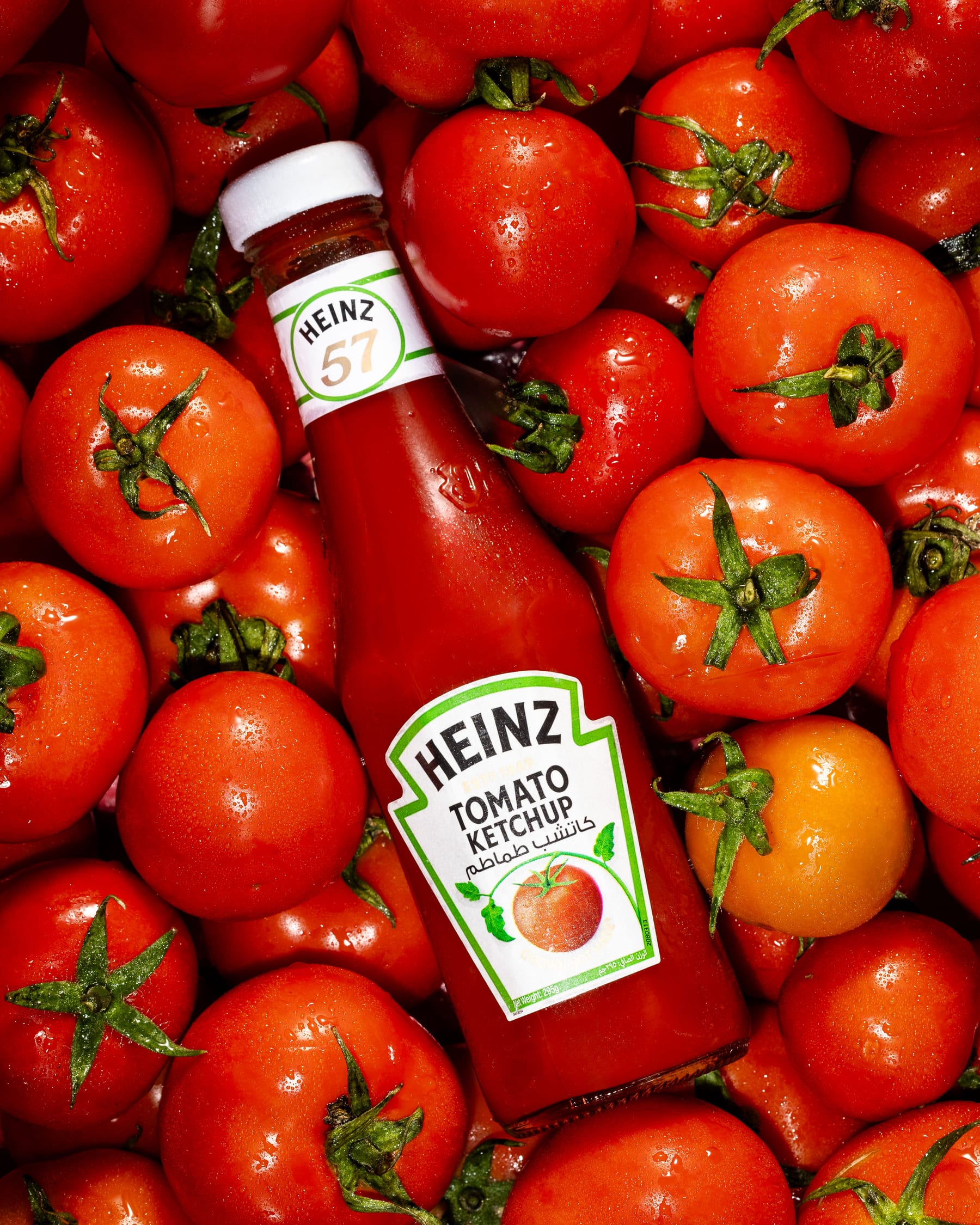 A Heinz tomato ketchup bottle lying in a dense bed of ripe tomatoes