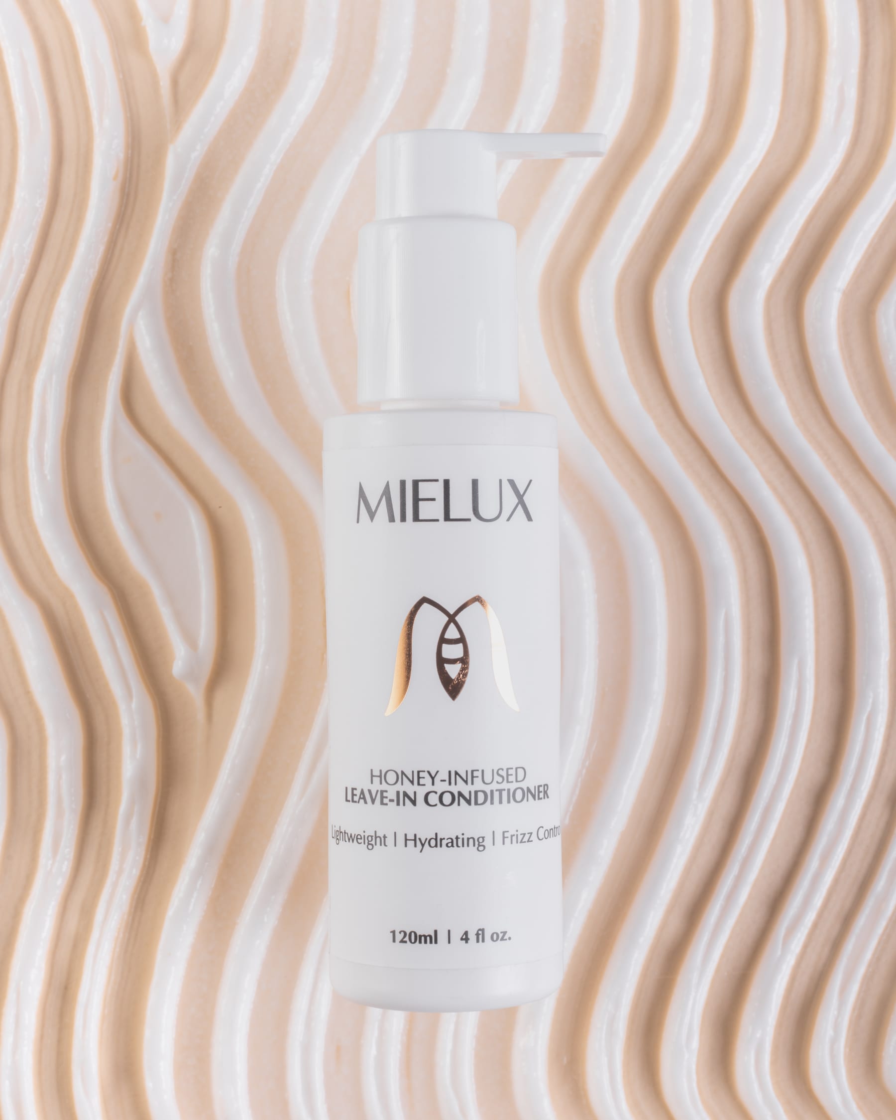 A Mielux honey-infused leave-in conditioner bottle standing against a rippled cream backdrop